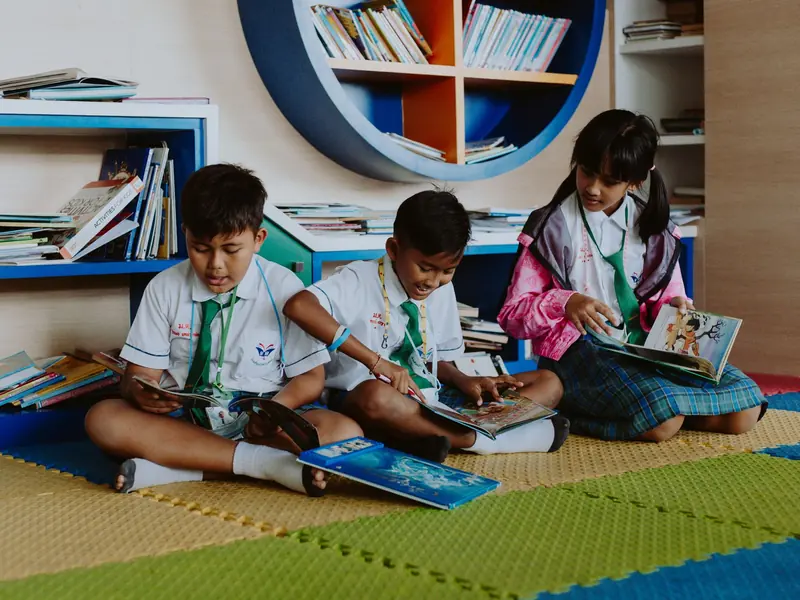 Children sitting on the library floor with picture books open in their laps.